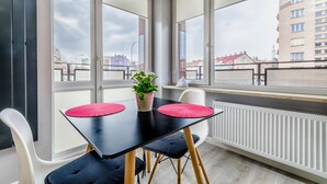 A modern dining area with a black table, two red placemats, a potted plant, and white chairs.