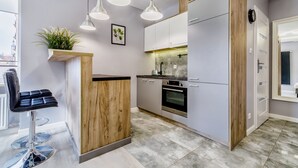 A modern kitchen with white cabinets, a wooden accent wall, and pendant lighting.