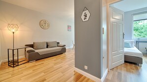 A modern living room with a grey sofa, a geometric floor lamp, and a wall clock.