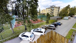 A parking area with several cars, a sports field, and residential buildings in the background.