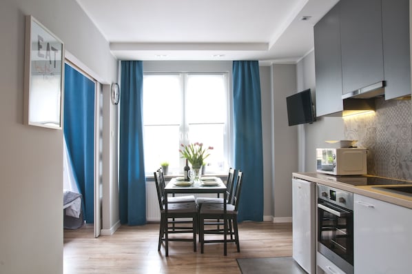 A modern kitchen with a dining table, chairs, a microwave, and a built-in oven.