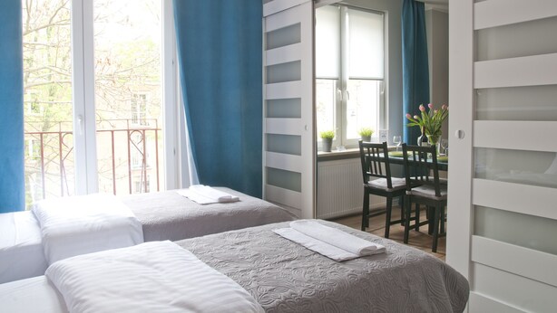 Ein Hotelzimmer mit zwei Betten, einem Essbereich mit Tisch und Stühlen sowie Blick ins Freie.