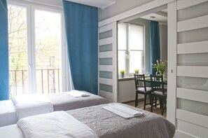A hotel room with two beds, a dining area with a table and chairs, and a view of the outside.