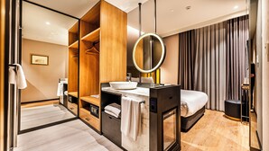 A modern hotel room with a wooden wardrobe, a round mirror, a white sink, and a bed with a black headboard. - Lamartine Hotel Istanbul (Istanbul)