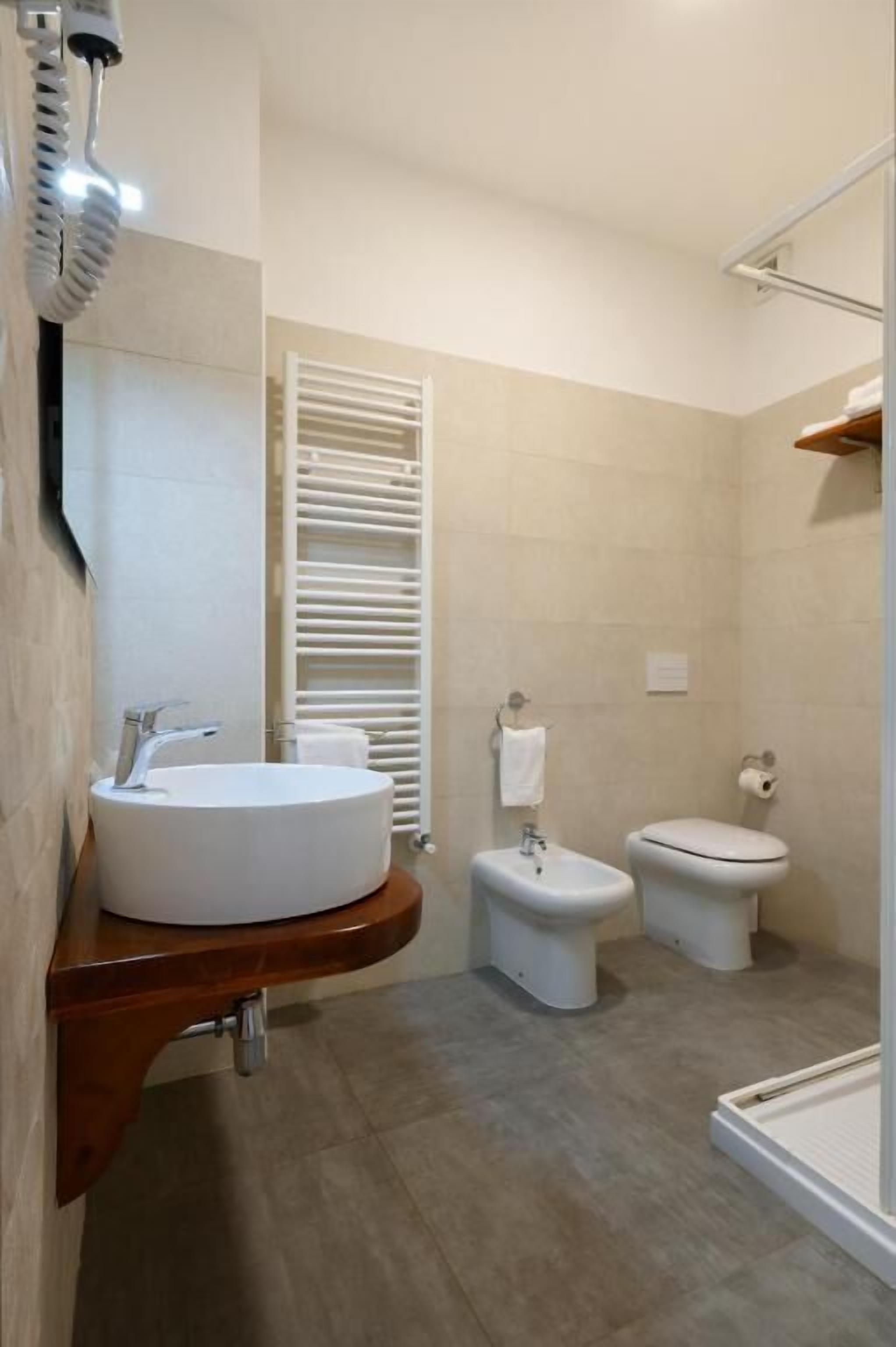 Une salle de bain équipée d’un lavabo, d’un bidet, de toilettes et d’un espace douche.
