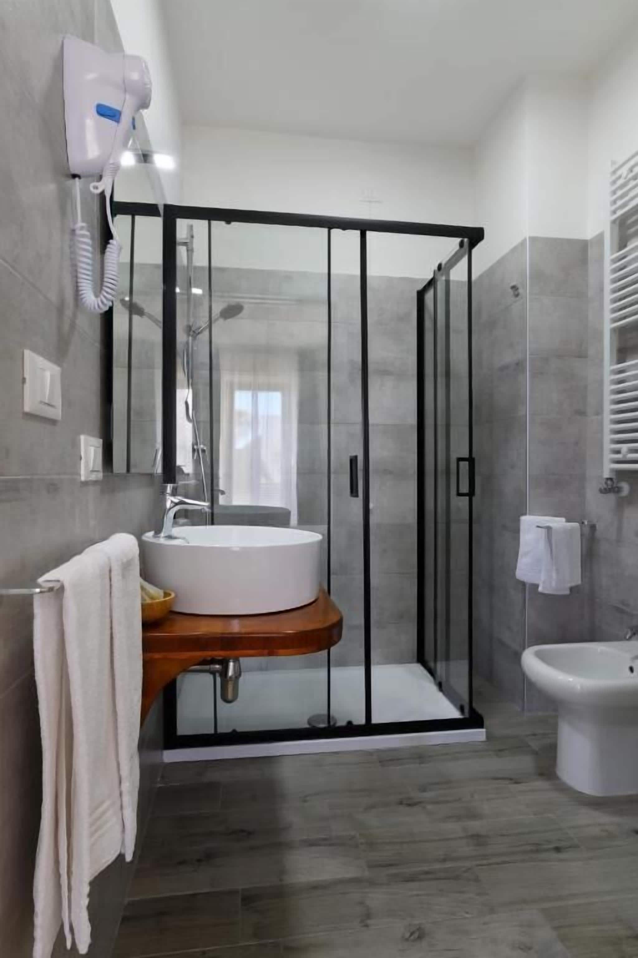 Un baño moderno con cabina de ducha de vidrio, un lavabo con encimera de madera y un inodoro.