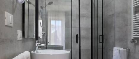 Un baño moderno con cabina de ducha de vidrio, un lavabo con encimera de madera y un inodoro.