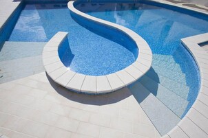 Una piscina al aire libre de temporada, sombrillas