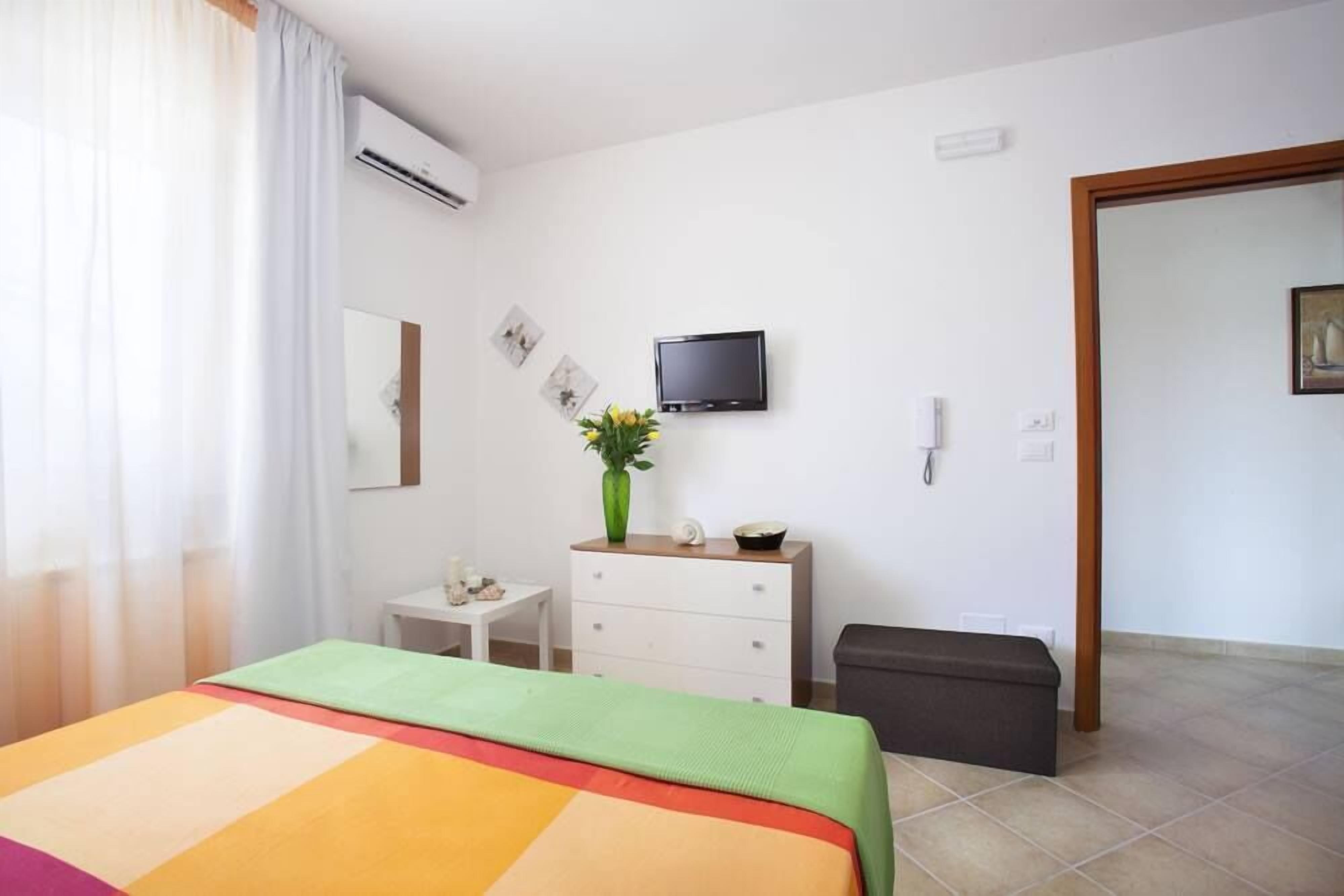 Une chambre d’hôtel équipée d’un lit, d’un petit bureau, d’une commode, d’une télévision et d’un appareil de climatisation.