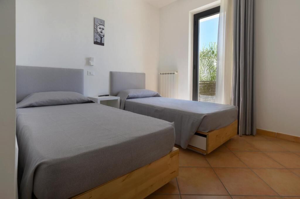 Un dormitorio con dos camas, una ventana con cortinas y un radiador.