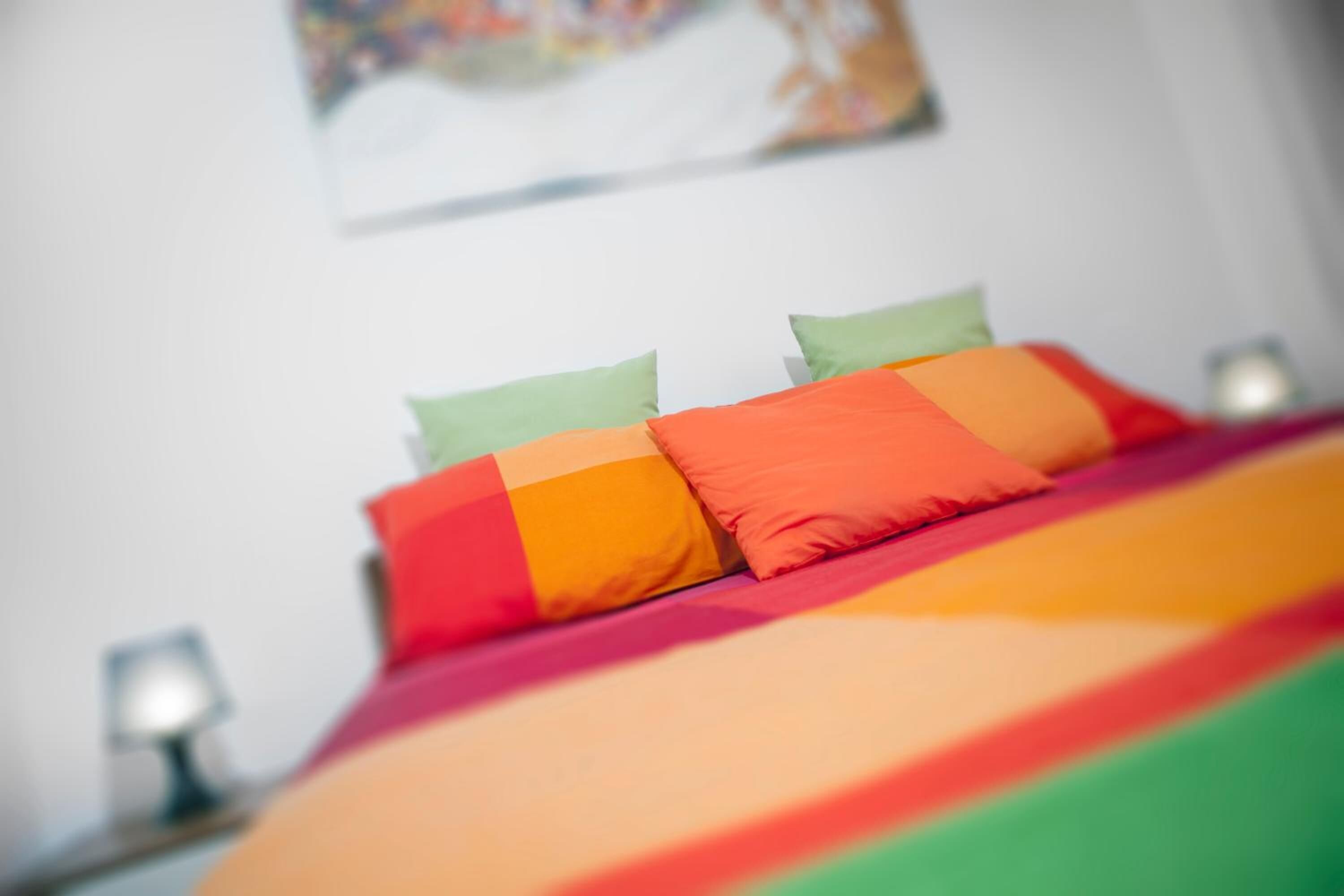 Una cama con una colcha y almohadas de colores del arcoíris.