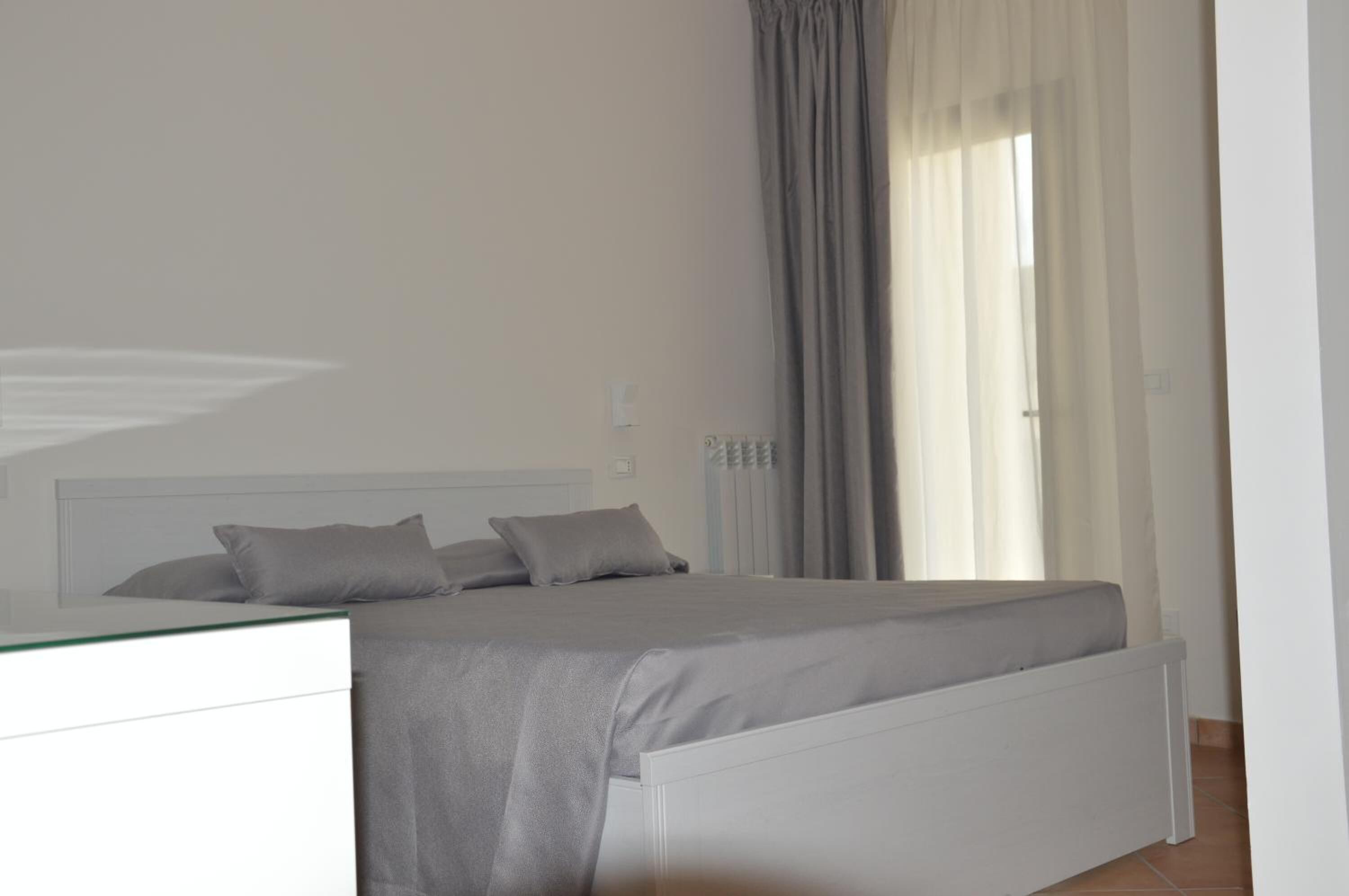 A bedroom with a bed, a bedside table, and a window with curtains.