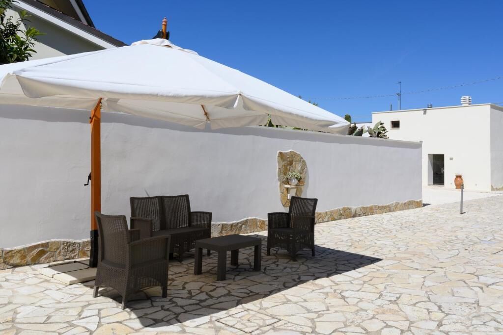 An outdoor seating area with wicker furniture and a white umbrella.