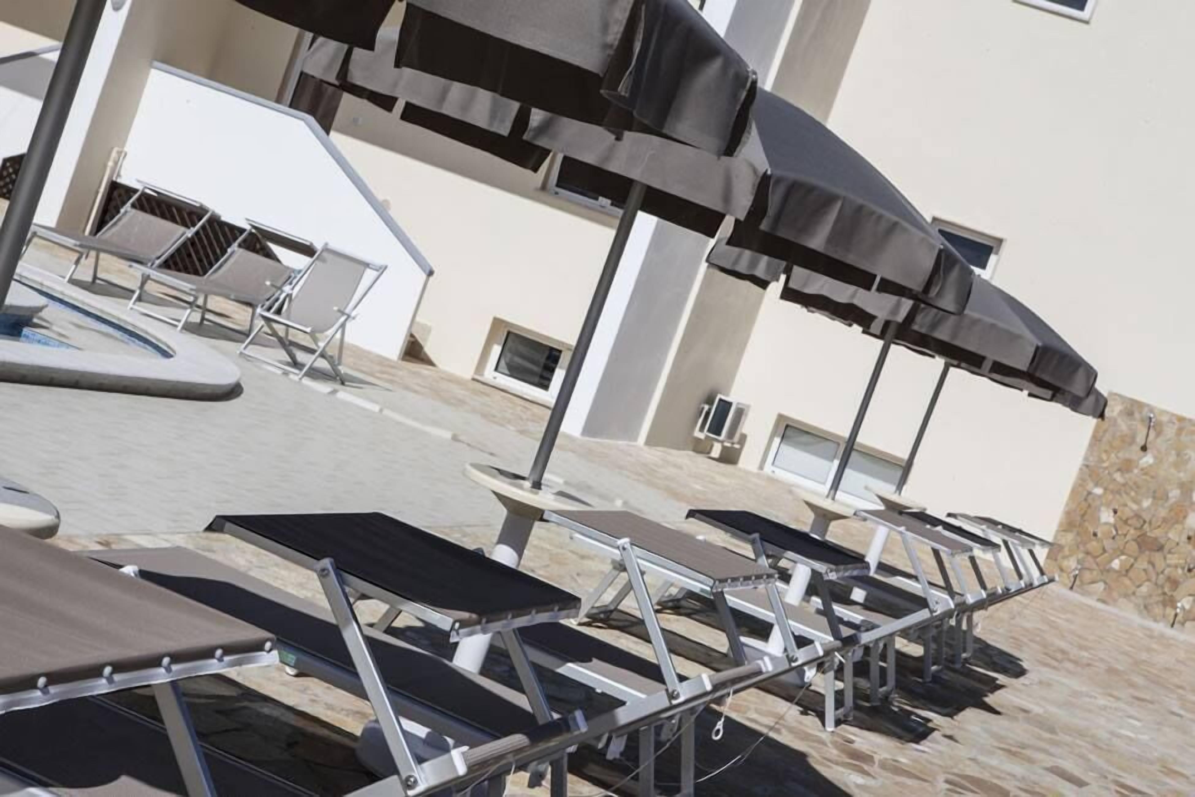 Outdoor seating with umbrellas, a pool, and a building with a stone wall.
