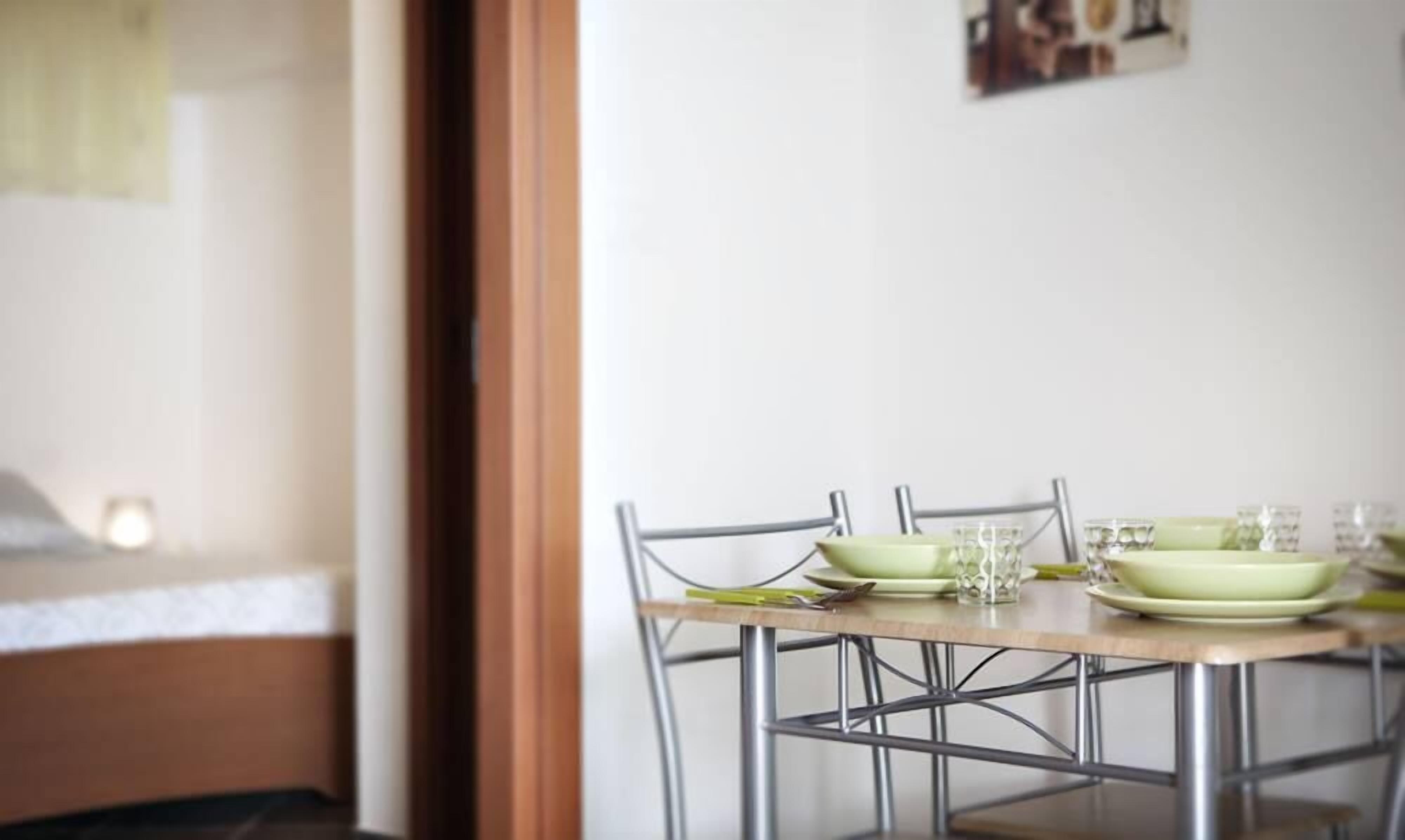 A dining area with a table set for two, featuring metal chairs and a wooden table.