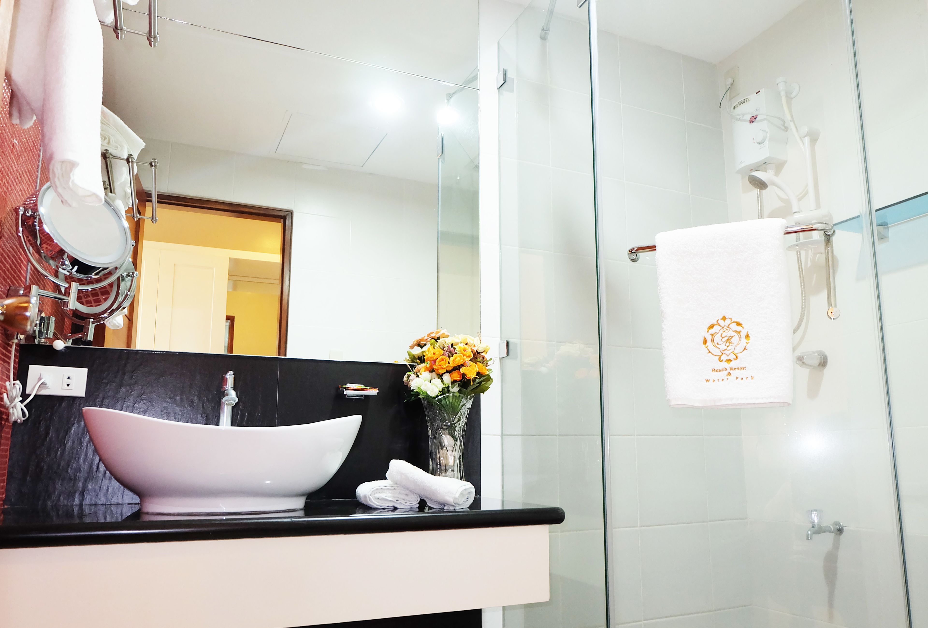 A modern bathroom with a large white sink, a glass shower enclosure, and a towel rack with a white towel.