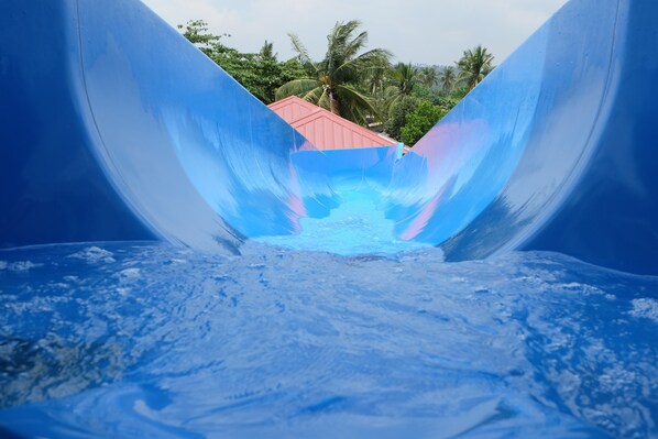 A water slide with a red roof at the top, surrounded by greenery. - CML Beach Resort & Water Park (Lemery)