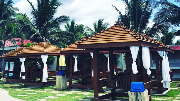 A gazebo-style structure with white curtains, surrounded by palm trees and a clear sky. - CML Beach Resort & Water Park (Lemery)