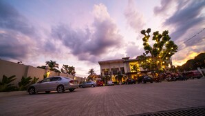 A parking lot with several cars and a building with multiple floors and balconies. - CML Beach Resort & Water Park (Lemery)