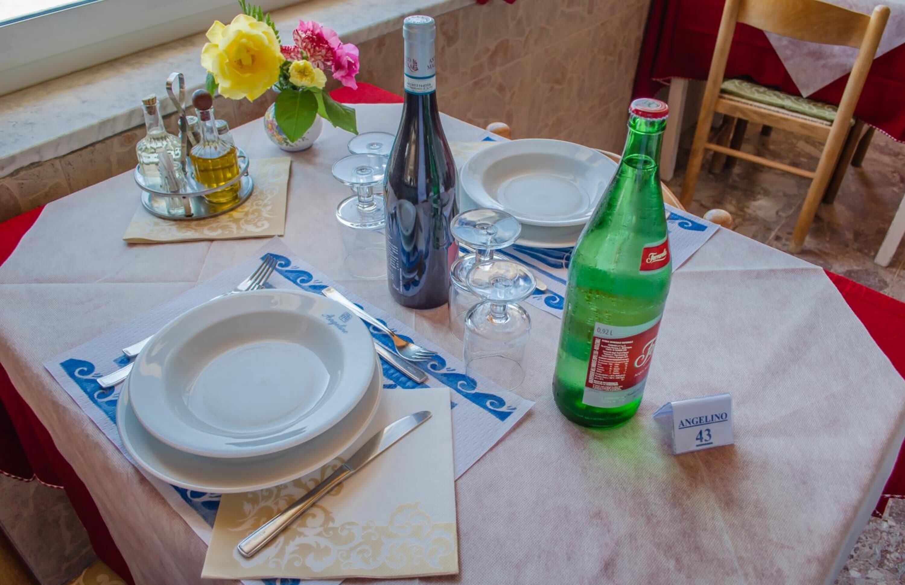 A table set for dining with plates, cutlery, and a bottle of Angelino wine.