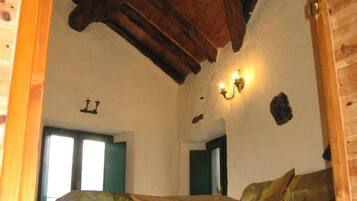 Une pièce avec un plafond en bois, deux lits, un luminaire fixé au mur et une porte dotée d’un cadre vert.
