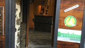 Una entrada de madera con un muro de piedra, un cartel que dice 'Bed & Breakfast' y 'Arcobaleno Casa Vacanze', y un suelo de baldosas.