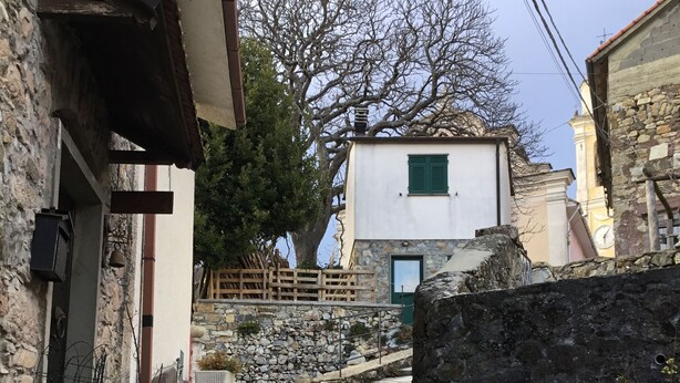 Una escalera de piedra que lleva a un edificio con fachada blanca y contraventanas verdes.