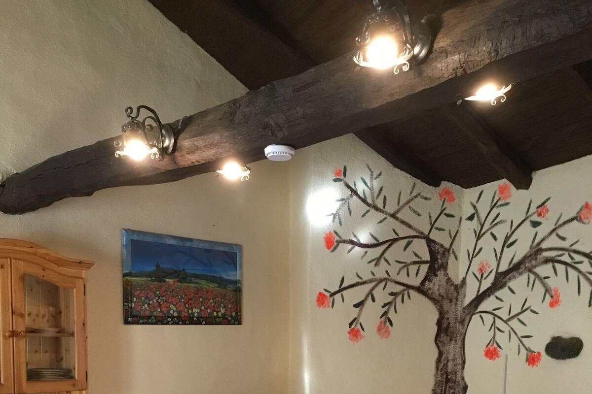 Een gezellige slaapkamer met een bed, een houten hoofdbord, een schilderij van een boom en een houten kast.
