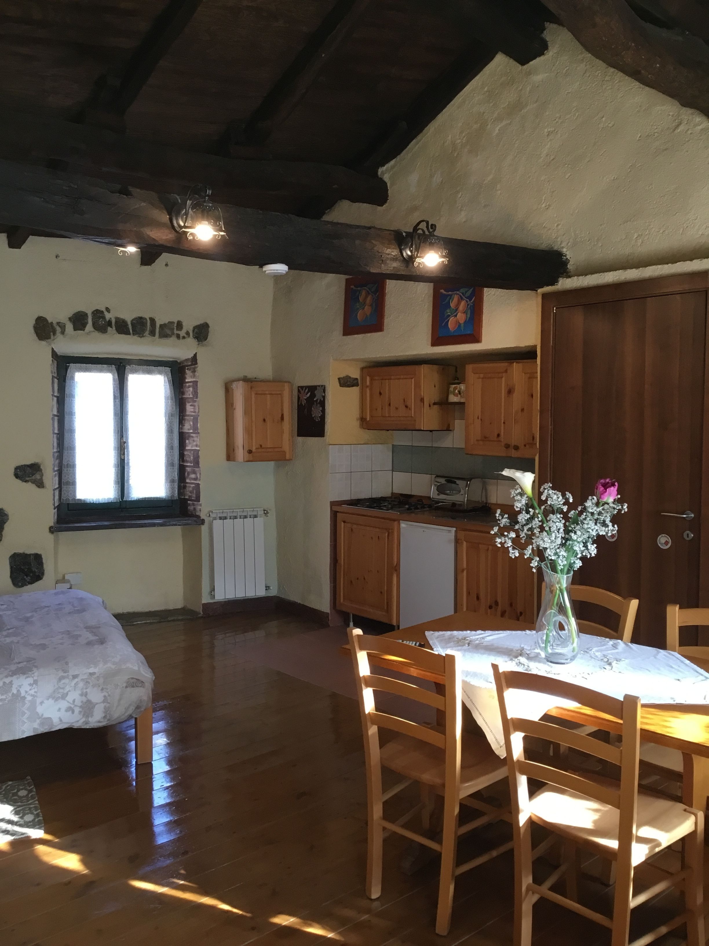 Una cucina rustica con mobili in legno, un tavolo da pranzo con sedie e una finestra con tende.