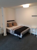 Quarto com cama, mesas de cabeceira e luminária suspensa.