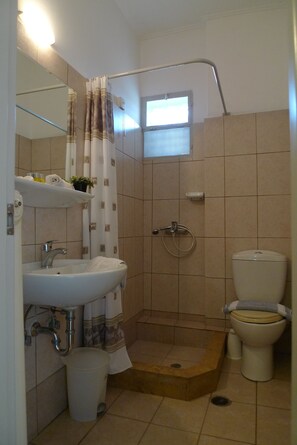 A bathroom with a shower, toilet, sink, and a small window. - Hotel Ikaros (Elliniko-Argyroupoli)