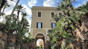 Un bâtiment à la façade beige, doté de nombreuses fenêtres et d’une entrée en arc de cercle.