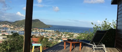 A wooden deck with a view of a coastal town and the sea.
