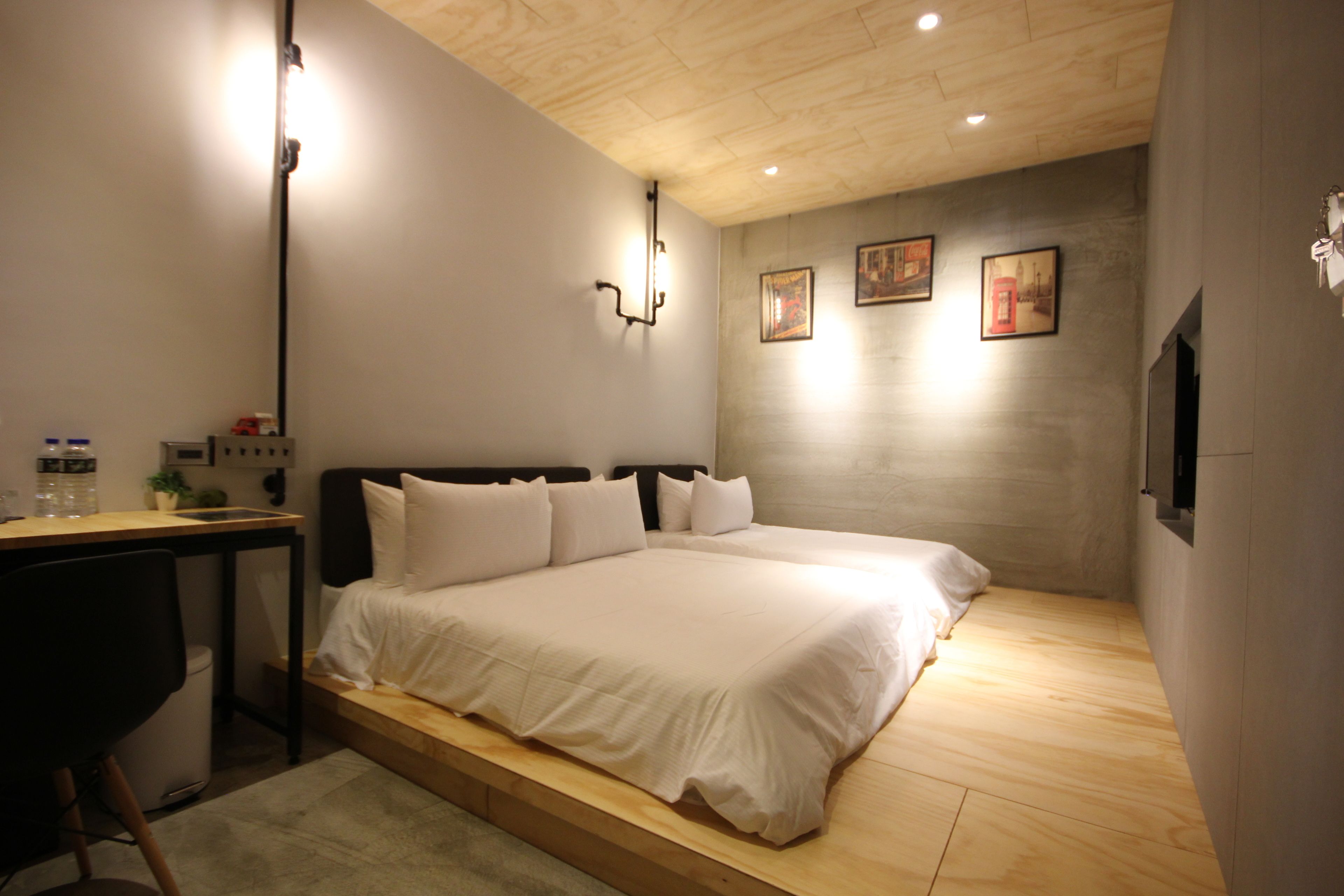 Une chambre à coucher avec un lit, un bureau et une chaise. Des lampes murales et des tableaux encadrés ornent le mur.