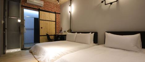 A hotel room with two beds, a brick wall, and a sliding door leading to a balcony.