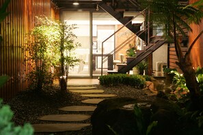 A modern interior with a staircase, indoor plants, and a stone pathway leading to a bright room. - Timing House (Yuchi)