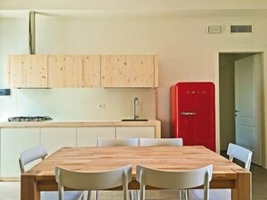 Una cocina moderna con armarios de madera, un refrigerador rojo y una mesa de comedor con sillas.