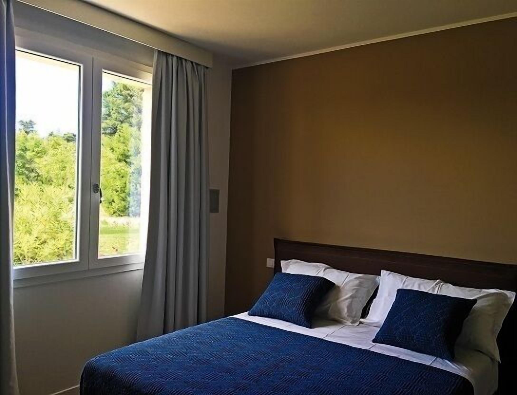 Une chambre d’hôtel avec un lit, une fenêtre avec des rideaux et une vue sur la verdure.
