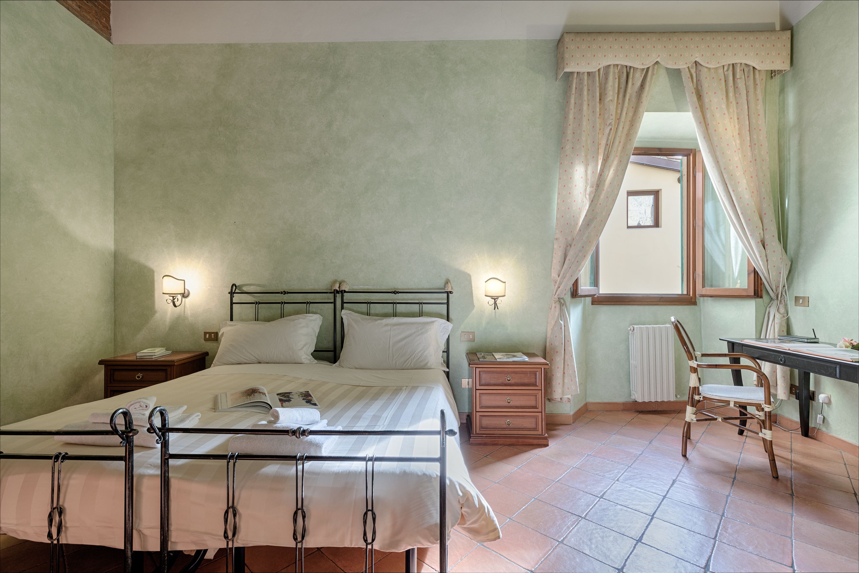 A bedroom with a bed, bedside tables, a desk, and a chair.