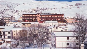 A hotel with multiple floors, balconies, and a snow-covered mountainous backdrop. - Hotel Campo Felice (Lucoli)