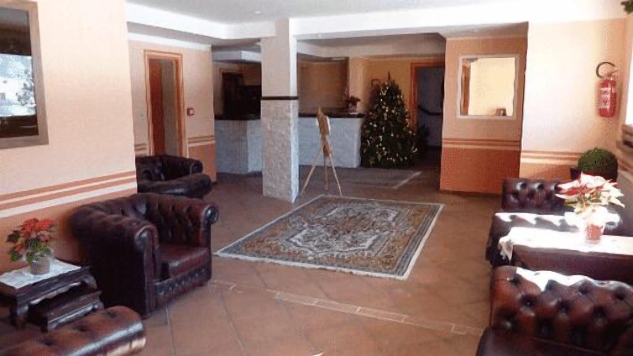 A spacious lobby with leather armchairs, a central rug, and a Christmas tree.