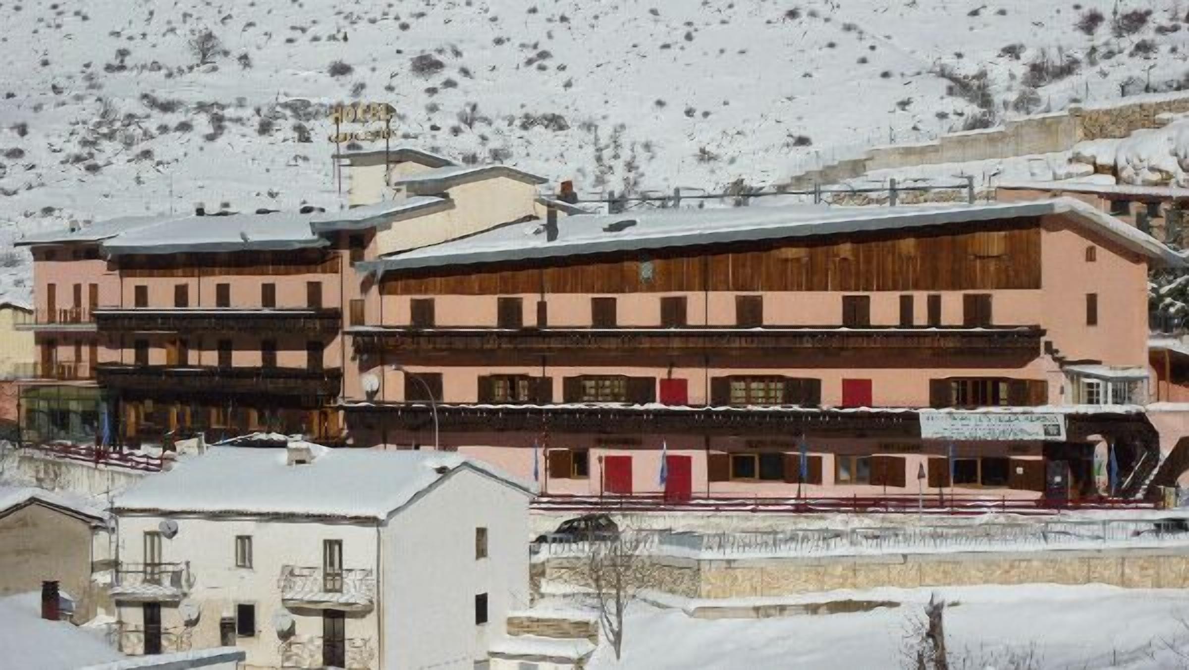 Un edificio a più piani con balconi e una seggiovia sullo sfondo.