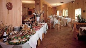 A restaurant with wooden walls and a long dining area. Tables are set with white tablecloths and various dishes. - Hotel Campo Felice (Lucoli)