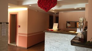 A reception area with a white brick counter, a red heart decoration on the ceiling, and a sign with emergency instructions. - Hotel Campo Felice (Lucoli)
