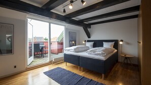 Un dormitorio con una cama grande, una puerta corrediza de vidrio a un balcón y techo de madera.