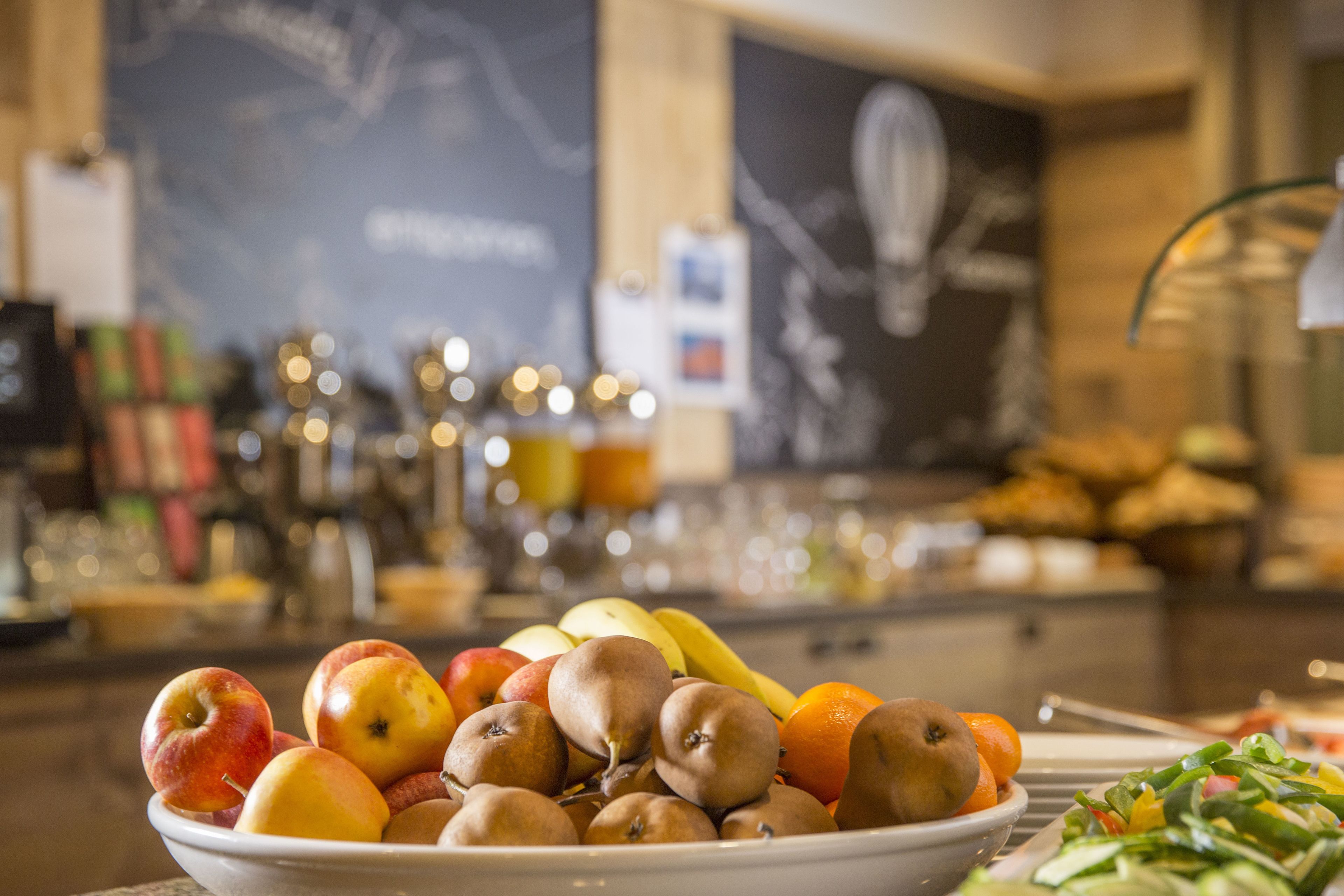 Uma tigela com frutas como maçãs, peras e laranjas sobre uma mesa.