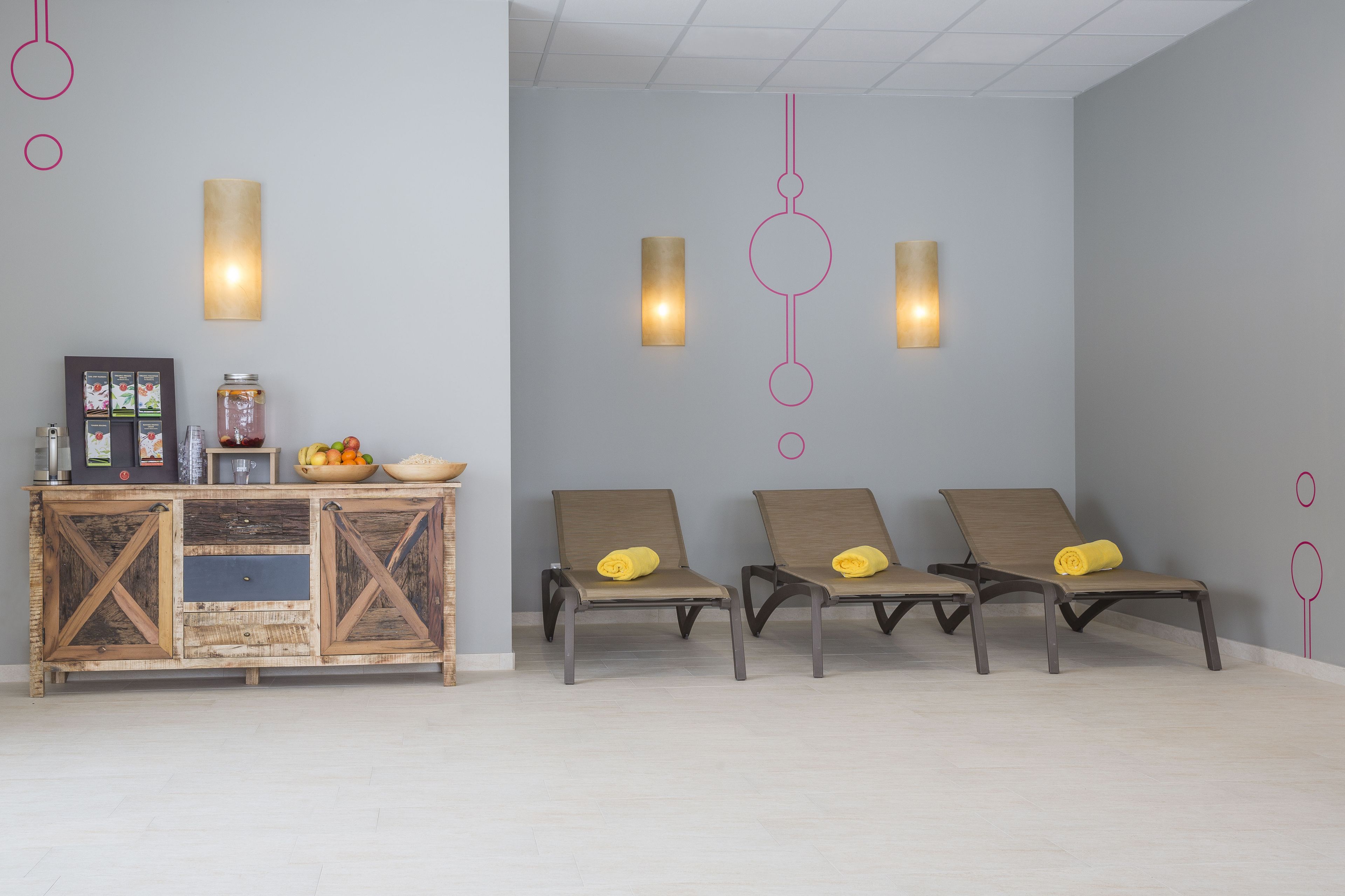 A modern lobby with a wooden console table, two wall-mounted lights, and three lounge chairs.
