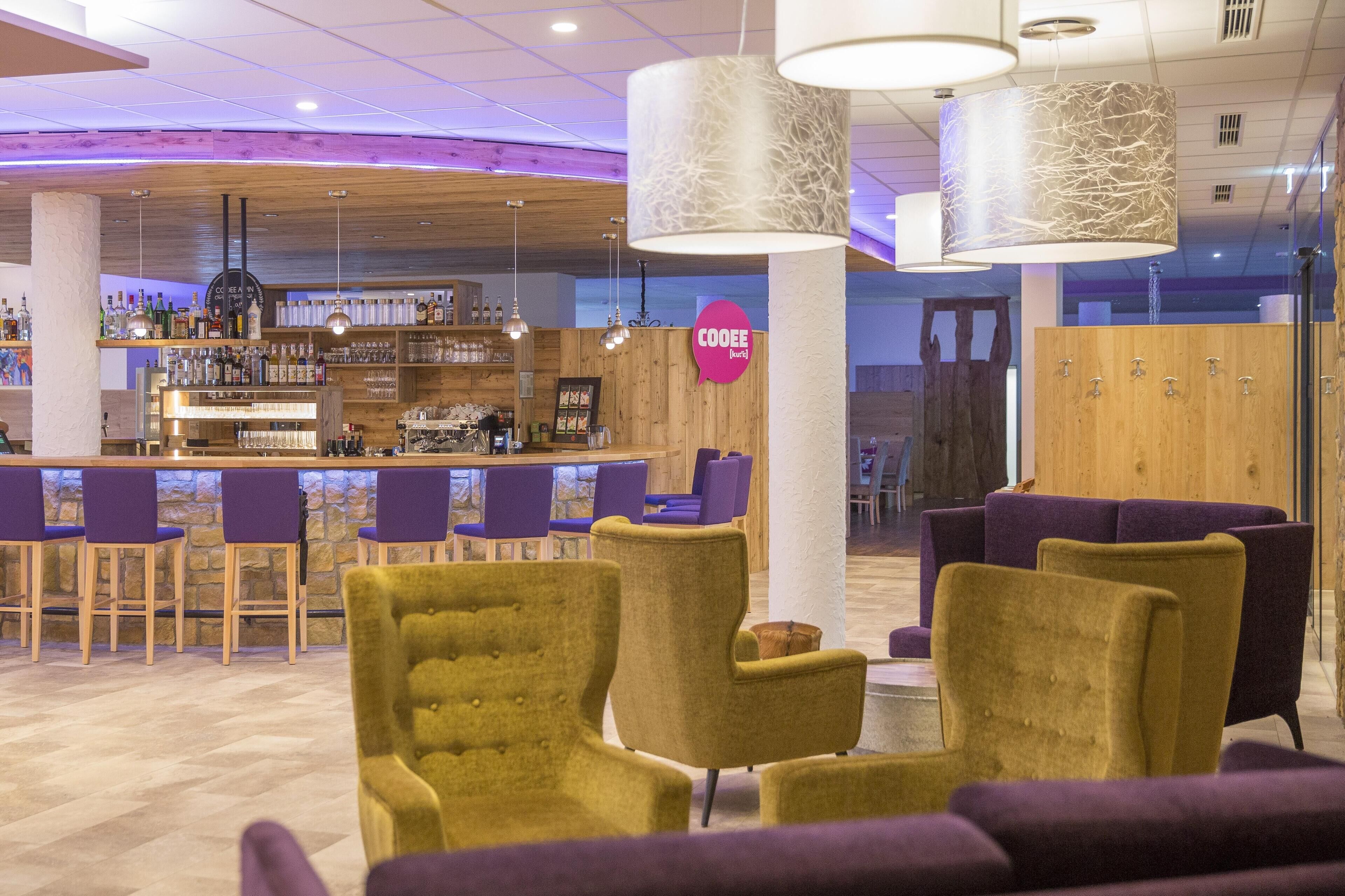 A bar area with purple chairs, a wooden counter, and a sign that reads "COOEE."