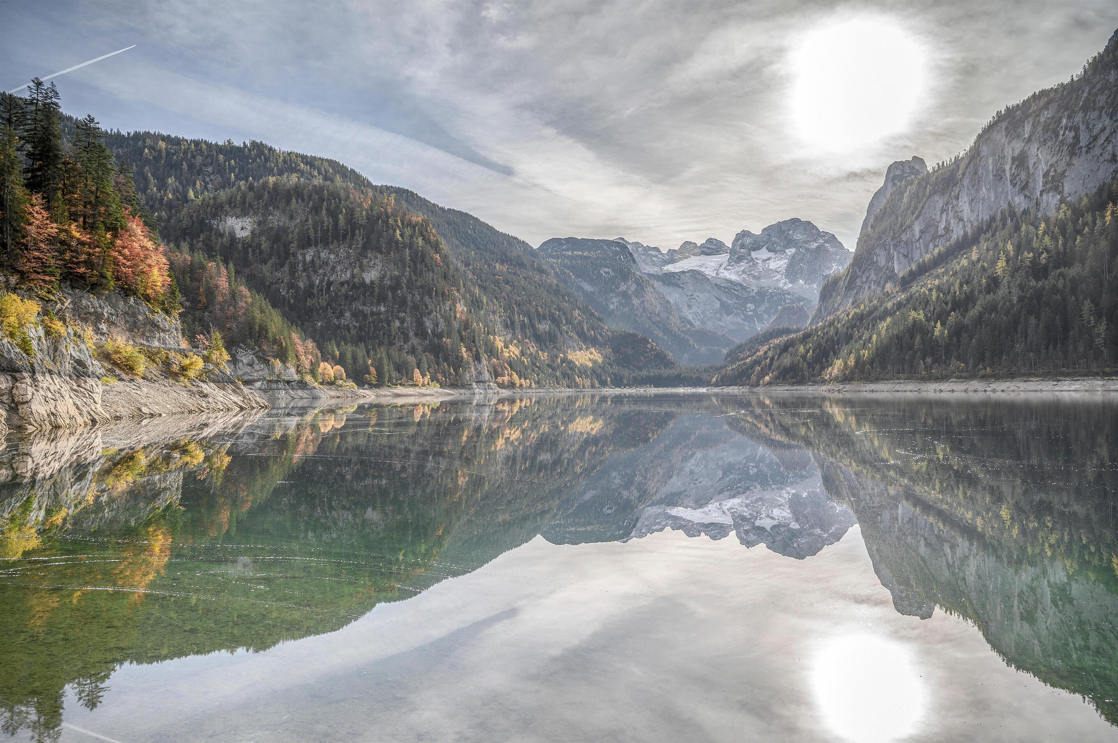Un lago tranquilo que refleja montañas y árboles.