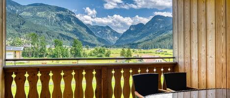 A wooden balcony with a view of mountains and a valley.